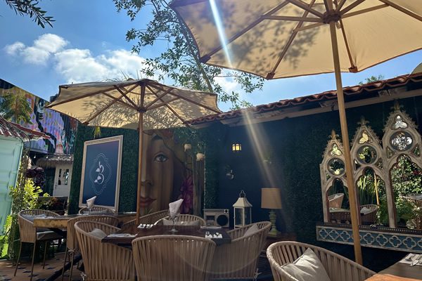 Las sombrillas crema del jardín, un mural y los espejos de arco entre la hiedra